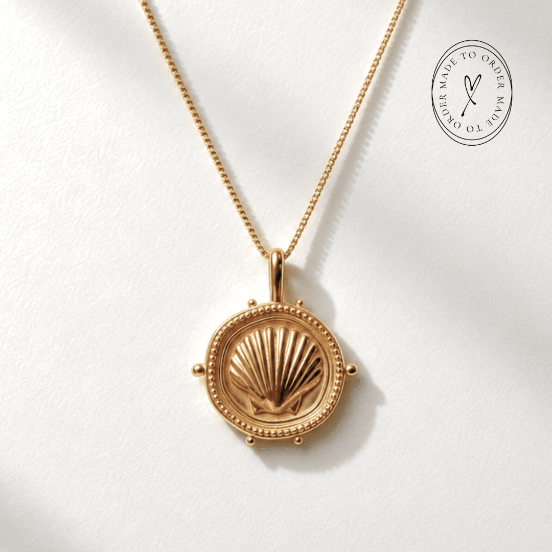 The Mermaid's Coin - a 2cm round gold disc pendant featuring a bold seashell motif and the Latin inscription 'Fluctuat nec mergitur', handcrafted by Dainty London.